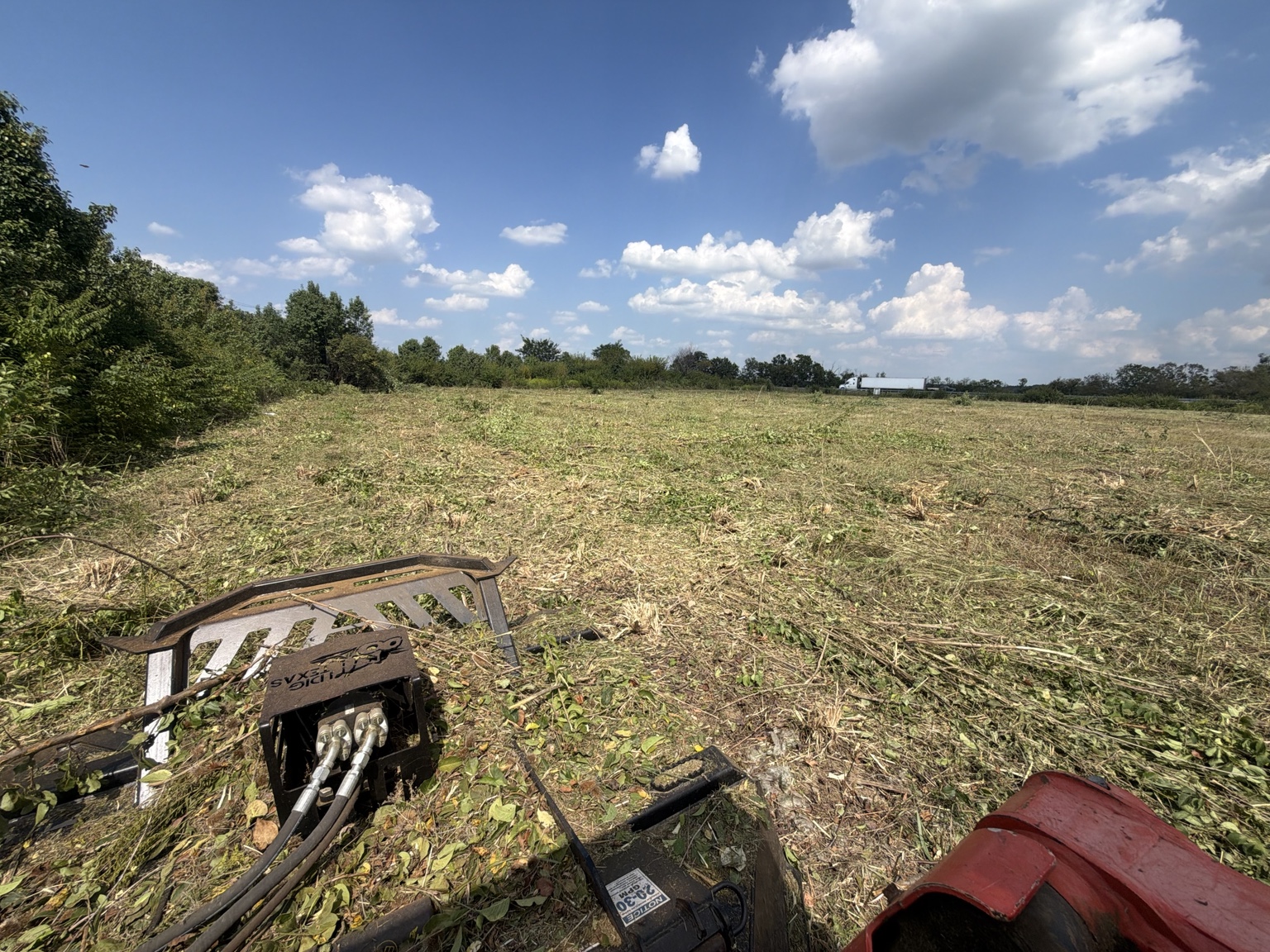 Field after brush clearing with equipment in the foreground